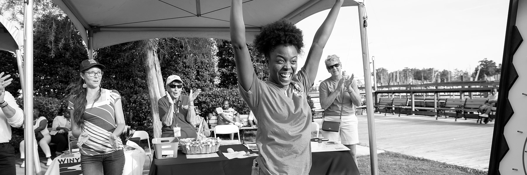 woman with her arms raised and 3 others in the background clapping