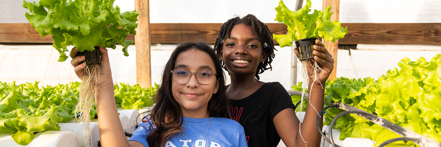2 girls smiling holding plants